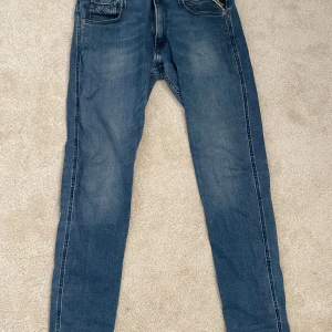 Blå Replay Anbass jeans - Säljer ett par klassiska blå Replay Anbass jeans. Jeansen har normal passform och raka ben, perfekta till vardags. Tidlös design med diskreta detaljer på bakfickorna. Storlek 32, 32