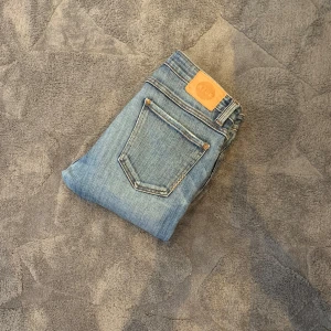 Ljusblå jeans från Neuw - Säljer ett par klassiska ljusblå jeans från Neuw med raka ben och femficksdesign. Jeansen har en snygg tvätt och detaljerade sömmar, samt läderpatch med Neuw-logga bak i midjan.