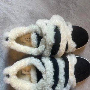 Svarta sneakers med vit fuskpäls från Inuikii - Säljer ett par svarta Inuikii sneakers. Aldrig använda, har ingen förpackning tyvärr kvar då jag trodde jag skulle använda dom.  Super fina men var inte min stil!! Perfekt att fixa nya skor redan nu till nästa vinter!!❤️