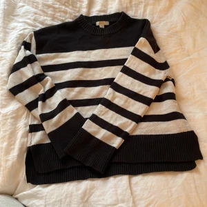 Svart och vit randig stickad tröja från Gina Tricot - Säljer en stickad tröja från Gina Tricot i svart och vitt med breda horisontella ränder. Tröjan har rund halsringning, långa ärmar och ribbade muddar vid ärmslut och nederkant. Perfekt för en avslappnad och stilren look.