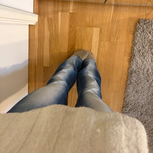 Weekday jeans  - Säljer ett par blå bootcut jeans från Cheap Monday med klassisk femficksdesign och snygga slitningar. Jeansen har normal passform och är tillverkade i en bomullsblandning med lite stretch för extra komfort. Små i storlek då jag själv har 27/34 i Ltb. 