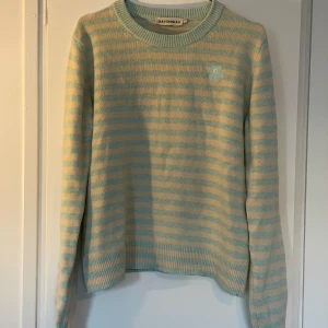Randig stickad tröja från Marimekko - Superfin stickad tröja från Marimekko i ljusblått och beige med smala ränder. Rund halsringning och lång ärm. Söt broderad blomdetalj på bröstet. Perfekt för dig som gillar stilrena men lekfulla plagg. Damstorlek L, sitter som S/M på herr. 