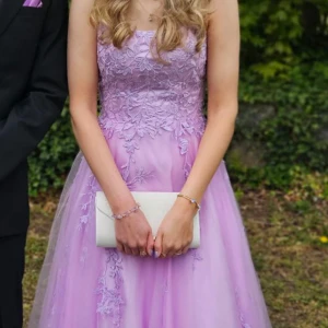 Ljuslila långklänning med spets och snörning - Säljer en drömmig ljuslila långklänning med tunna axelband, spetsdetaljer och vacker snörning i ryggen. Klänningen har utsvängd kjol i flera lager och fina broderade blommor framtill. Perfekt som balklänning! Kontakta för fler bilder eller funderingar💜