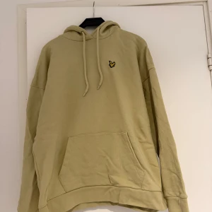 Beige hoodie från Lyle & Scott - Säljer en beige hoodie från Lyle & Scott i 100% ekologisk bomull. Tröjan har huva med dragsko, magficka och den klassiska broderade loggan på bröstet. Perfekt för en avslappnad stil. Skick är helt perfekt. Storlek M