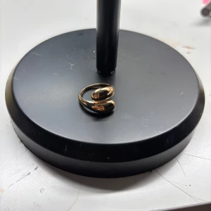 Guldfärgad ring med modern design - Säljer en stilren guldfärgad ring med en öppen, böjd form som ger en modern och trendig känsla. Perfekt accessoar för att lyfta din outfit med en elegant touch.