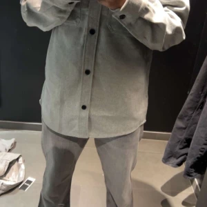 Grå overshirt från H&M, storlek S - Säljer en stilren grå overshirt från H&M i regular fit. Skjortan har två bröstfickor med lock, svarta knappar hela vägen och klassisk krage. Perfekt lager-på-lager-plagg med lång ärm och mjukt material. Perfekt till hösten och våren. Funkar både som jacka och overshirt. Väldigt skön och enkel att matcha med det mesta.  📍 Finns i Stockholm- Sollentuna  📬 Möts upp – ingen frakt 