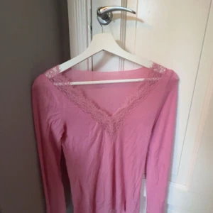 Rosa långärmad topp med spets - ‼️PRIS KAN DISSKUTERAS‼️Säljer en söt rosa långärmad topp med v-ringning och fina spetsdetaljer. tröjan är andvönd fåtal gånger!  Toppens material känns lätt och bekvämt mot huden.