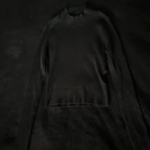 Svart ribbad stickad tröja Even&Odd - Svart ribbad stickad tröja från Even&Odd med lång ärm och hög hals. Tröjan har en tight passform och är perfekt för lager-på-lager. Enkel och stilren design som funkar till många olika looks.