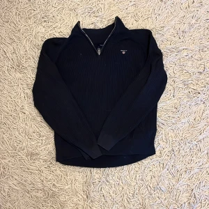 stickad half zip tröja från Gant -  ribbstickad tröja från Gant med halv dragkedja och broderad logga på bröstet. Tröjan har lång ärm och hög krage, perfekt för lager-på-lager. Klassisk och stilren modell som funkar till det mesta. Storleken är 13-14 år och passar ungefär dig som är 158-164. Hör av er vid frågor eller fler bilder.