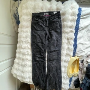 Svarta jeansbyxor från Mos Mosh - Snygga svarta jeansbyxor från Mos Mosh med diskret mönster och klassisk femficksdesign. Byxorna har utsvängda ben och dragkedja i gylfen. Insidan av linningen har en cool rosa detalj som sticker ut. Perfekta för dig som gillar en stilren men unik look.