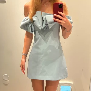 Blå miniklänning från Zara - Supersöt miniklänning med rosetter som inte säljs längre. Helt oanvänd med prislappen kvar. Nypris 499 kr. Som referens är jag ca 176 cm lång.