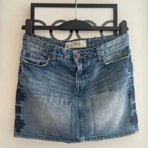 Jeanskjol med spets från H&M L.O.G.G. - Snygg jeanskjol från H&M L.O.G.G. i klassisk blå denim med coola mörkblå spetsdetaljer längs sidorna. Kjolen har fem fickor, knapp och dragkedja framtill samt en rak, kort passform. Perfekt för dig som gillar en avslappnad men trendig stil. Skriv om du undrar något, kolla min profil innan du trycker på köp nu💗💗💗