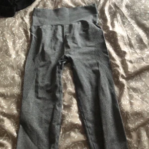 Grå höga tights från Aim'n - Mörkgrå höga tights från Aim'n med bred midjeresår och diskret meshdetalj längs sidorna. Stretchigt material som sitter tight och är perfekt för träning eller chill. Snygg och enkel design som funkar till det mesta.