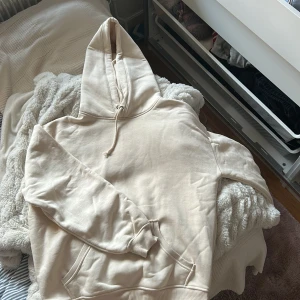 Beige hoodie från BikBok XS - Snygg beige hoodie från BikBok i storlek XS. Tröjan har huva med snörning, magficka och långa ärmar. Perfekt för en chill och avslappnad stil. Mjuk insida och lite oversize passform. 