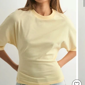 Gul topp med knyt i ryggen Nelly  - Snygg ljusgul  topp med korta ärmar och rund halsringning. Baksidan har öppen rygg och ett brett knytband som ger en unik look. Perfekt till jeans för en chill och trendig stil. Aldrig använd, slutsåld i denna storlek☺️