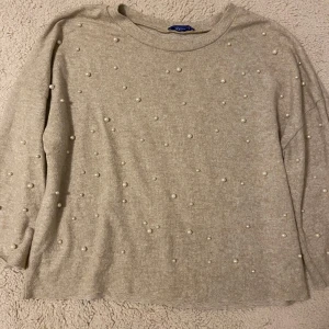 Beige tröja med pärlor från Zara - Superfin beige tröja från Zara med pärldetaljer framtill. Tröjan har en rak passform, rund halsringning och 3/4 ärmar. Mjuk och skön, perfekt för dig som gillar en enkel men ändå extra look🍁✨🌆