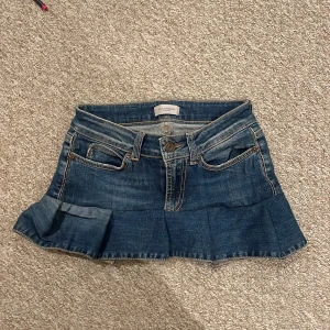 Jeanskjol med volang  - Mörkblå jeanskjol från Hunkydory med volang nertill och klassiska fickor både fram och bak. Storleken står inte men tror den är typ xxs. Midjemåttet är ungefär 68 cm. 
