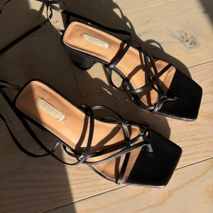 Klackar med snörning - Stilrena svarta sandaler från Arket med fyrkantig tå, tunna remmar och blockklack. Skorna har snörning som kan lindas runt vristen och är tillverkade i äkta skinn.💓