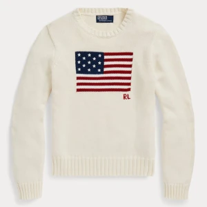Vit stickad tröja Polo Ralph Lauren - Vit stickad tröja från Polo Ralph Lauren med amerikansk flagga och RL-brodyr framtill. Rund halsringning och ribbade muddar vid ärmslut och nederkant. Perfekt för dig som gillar klassisk och stilren design.