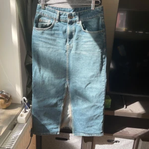 Jeanskjol från Massimo Dutti - Snygg blå lång jeanskjol från Massimo Dutti med klassiska fickor och en slits i mitten fram och bak, bälteshällor och slits framtill. Kjolen har knapp och dragkedja i midjan.