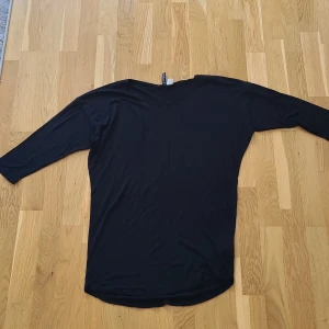 Svart topp  - Enkel svart topp med halvt långa armar. Tunt och mjukt material som känns skönt mot huden.