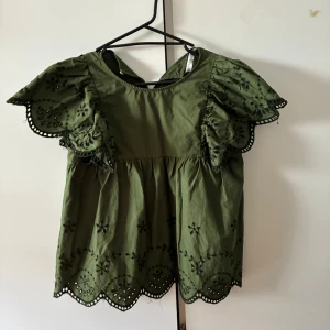 Grön blus med broderade volangärmar - Supersöt grön blus med broderade detaljer och volangiga korta ärmar.