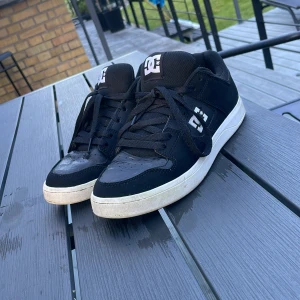 Svarta DC Cure sneakers i skinn - Svarta DC Cure sneakers med vit sula och klassisk DC-logga på sidan och plösen. Skorna har snörning, rund tå och är tillverkade i skinn med gummisula. Perfekta för skate eller streetstyle och riktigt bekväma att bära hela dagen.
