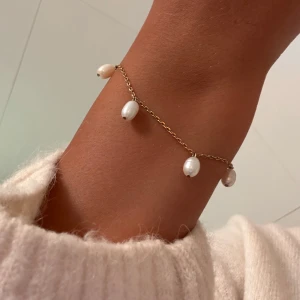 Guldfärgat armband med pärlor - Superfint armband från Edblad med tunn guldfärgad kedja och fem vita oregelbundna pärlor som hänger längs länken💗