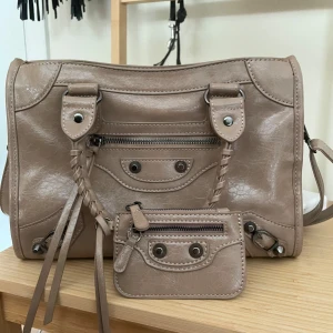 beige citybag med matchande plånbok - helt ny jättesnygg beige citybag med matchande plånbok, svårt att få färgen på bild men skulle säga att den är snäppet ljusare i verkligheten. finns två fack inuti, en av de har dragkedja. väldigt rymlig och får plats med mycket! 💕