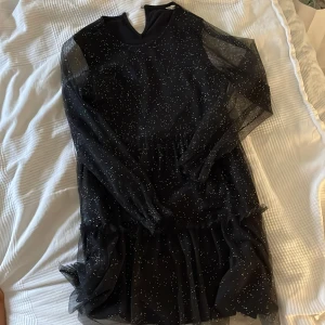 Svart glittrig klänning med nät - Supersnygg svart klänning med transparenta långa ärmar och glittriga detaljer över hela klänningen. (aldrig använd bara provad)