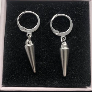 Silvriga örhängen med konformad detalj - Snygga silvriga örhängen med coola konformade hängen. De har en enkel ring som fäste och en stilren, minimalistisk design som ger en edgy vibe. Perfekta för dig som gillar att sticka ut med accessoarerna.