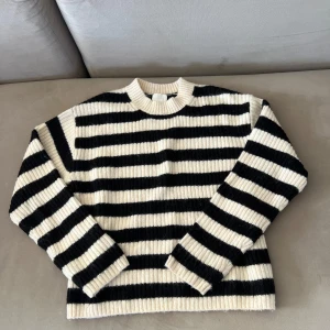 Randig svartvit stickad tröja - Snygg stickad tröja med breda svarta och vita ränder. Tröjan har rund halsringning, ribbade muddar och lång ärm. Perfekt för dig som gillar en klassisk men trendig look. Passar till jeans eller kjol för en chill stil.