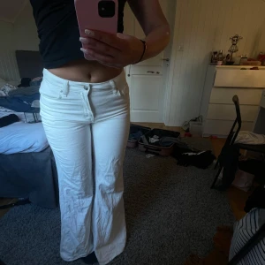 Vita bootcut jeans från Divided H&M - Säljer ett par vita bootcut jeans från Divided H&M i storlek 34. Byxorna är mid waist och är tillverkade i bomull. Snyggt utsvängda ben och stilren look som passar till många outfits.