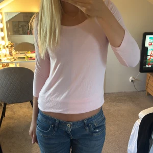 Ljusrosa långärmad topp i bomull - Säljer en ljusrosa långärmad topp med rund halsringning. Modellen är enkel och stilren, i mjuk bomull som känns skön mot huden. Perfekt till jeans eller kjol för en avslappnad look. Ärmarna är trekvarts och passformen är normal.
