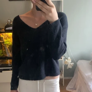 Svart stickad tröja med v-ringning 157 - Mysig svart stickad tröja från 157 i storlek XS. Tröjan har en snygg v-ringad hals och långa ärmar. Perfekt för lager-på-lager och passar till både jeans och kjol. Enkel och stilren design som funkar till det mesta.