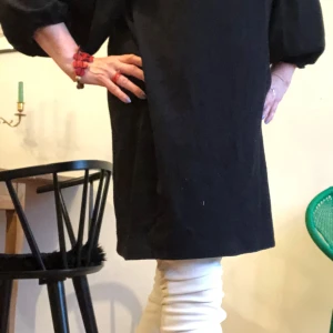 Svart kortklänning från Lindex - Svart kortklänning från Lindex med v-ringning och puffiga långärmar. Klänningen har en enkel, rak passform och är tillverkad i ett mjukt tyg med lite vågstruktur. . Perfekt för dig som gillar stilren och tidlös design. 95% polyester 5% elastan.