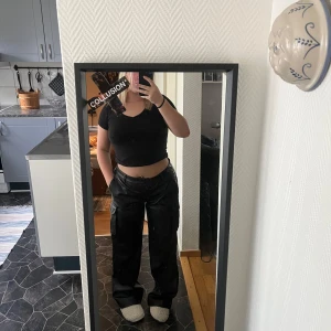Svarta cargopants i skinnimitation COLLUSION - Säljer ett par svarta cargopants från bikbok i skinnimitation. Byxorna har bred passform, sidofickor och raka ben. Helt nya och bara testade på! Säljer pga för stora 