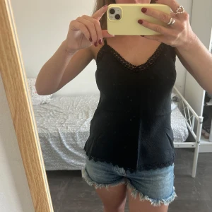 Svart topp - Säljer denna svarta linnetopp, som jag tyvärr aldrig använt men som har fina spetsdetaljer, köpt på i en liten lokalbutik på Mallorca