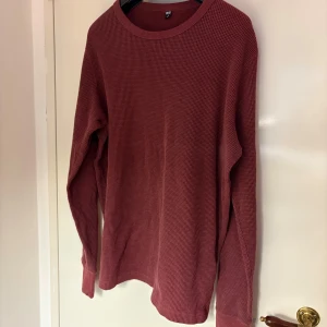 Roströd långärmad tröja från Uniqlo - Säljer en roströd långärmad tröja från Uniqlo i storlek M. Tröjan har en enkel, klassisk design med rund hals och är tillverkad i ett mjukt, ribbat material som ger en skön känsla. Perfekt för lager-på-lager eller som den är.