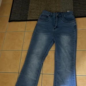 Blå bootcut jeans - Säljer ett par klassiska blå bootcut jeans med normal passform. Jeansen har fyra fickor, dragkedja och knapp framtill. Perfekta för dig som gillar en tidlös stil med lite utsvängda ben. Har aldrig använt dem.🌸