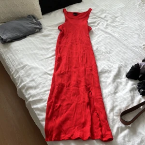 Röd ribbad långklänning Gina Tricot - Snygg röd långklänning från Gina Tricot i ribbad bomull. Ärmlös modell med rund halsringning och slits på sidan för extra vibe. Perfekt för dig som vill sticka ut med en enkel men bold look.