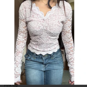 Ljusrosa spetsblus med lång ärm - Superfin ljusrosa blus i spets med långa ärmar och vacker vågig kant vid halsringningen. Blusen är figurnära och har ett romantiskt blommönster i spets. Perfekt för dig som vill ha en feminin och trendig look.