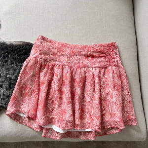 Rosa mönstrad kortkjol från Gina Tricot - Supersöt kortkjol från Gina Young!. Kjolen har volangig form och resår i midjan för en bekväm passform. Drömmig till i sommar, slutsåld och väldigt eftertraktad så skynda!! Nån söm som är lite lös på baksidan (se bild 3) men inget man tänker på, går lätt att fixa