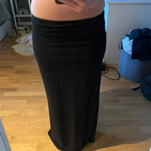 Svart långkjol från Gina Tricot - Säljer en svart långkjol från Gina Tricot. Kjolen har en rak och tight passform med låg midja och är tillverkad i ett mjukt och stretchigt material. Perfekt att styla med crop top eller stickad tröja.
