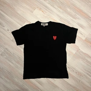Svart t-shirt från Comme des Garçons Play - Svart t-shirt från Comme des Garçons Play med det ikoniska röda hjärta-märket broderat på bröstet🤩Klassisk rund halsringning och korta ärmar. Perfekt för en stilren och trendig look.🔥