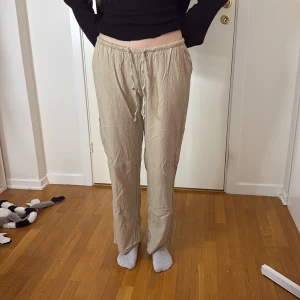 Beiga linnebyxor från hm XS - Säljer ett par beiga linnebyxor från hm i storlek XS. Byxorna har rak passform, resår i midjan och snörning framtill. Materialet är en blandning av viskos och linne, vilket gör dem lätta och sköna. Perfekta för en chill och avslappnad stil.