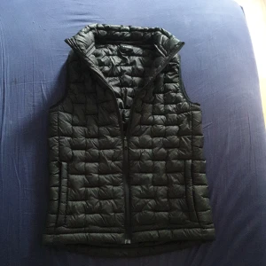 Svart Everest väst  - Svart dunväst med quiltad design och dragkedja framtill. Västen har hög krage och två fickor på både insidan och utsidan av västen.. Perfekt att slänga över en hoodie för extra värme. Snygg och enkel stil som funkar till det mesta. Säljs endast p.g.a att den är för liten annars är den i PERFEKT skick.