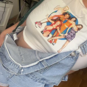 Vit Spice Girls crop t-shirt 90s  - Vit crop t-shirt med färgglatt Spice Girls-tryck på bröstet. T-shirten är kortärmad och har en tight passform. Perfekt för dig som vill ha en throwback till 90-talet och gillar ikoniska girlbands.  