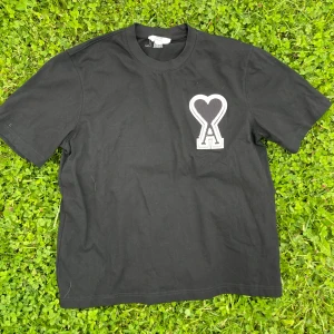 Svart t-shirt från AMI Paris - Svart t-shirt från AMI med stor vit och svart hjärtformad A-logga på bröstet. Klassisk passform och rund halsringning. Perfekt för sommaren. Det går även att köpa i ett set med shortsen, Kolla in profilen!🙌☀️