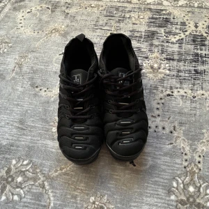 Svarta sneakers Nike vapormax med futuristisk sula - Säljer ett par helsvarta sneakers Nike vapormax med unik, vågig sula och snörning. Skorna har rund tå och platt sula, samt detaljer i syntetmaterial. Perfekta för dig som gillar en modern och sportig look.